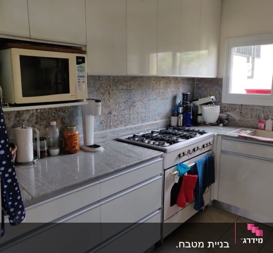 מטבח עם מיקרוגל, כיריים, כיור וכלים על השיש